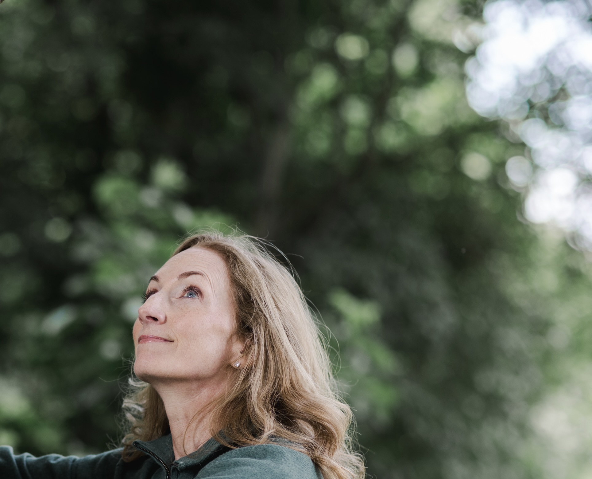 Pia with her face lifted toward the canopy in the forest
